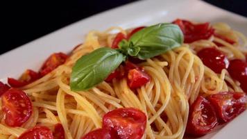 pomodoro spaghetti nel un' piatto, pronto per essere servito. servendo pasta con pomodori. pomodoro salsa e basilico. cursore sparo. tipico italiano pasto ristorante cibo. fatti in casa. italiano cibo video