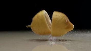 Fresh sliced lemon falling and splashing on water at slow motion video