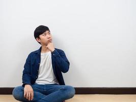 Asian man sit on floor thinking and looking at copy space photo