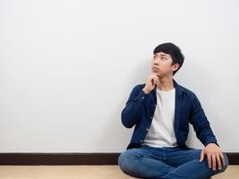 Asian man sit on floor thinking and looking at copy space photo