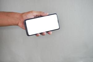 holding smart phone with empty screen on gray background photo