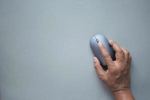 vista superior de la mano de la persona usando el mouse sobre fondo gris foto