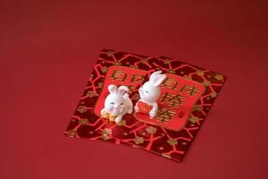 Chinese New Year of the rabbit festival concept. Rabbit on red envelopes isolated on red background. Happy New Year Chinese Rabbit 2023. Chinese characters means rich, wealthy, healthy and happy. photo