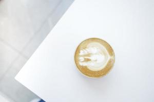 a cup of late coffee with flower shape design on top at cafe photo