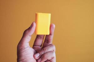 holding artificial sweetener container against yellow background photo