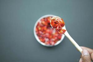 red chili flakes on wooden spoon top view photo