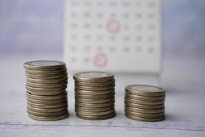 pila de monedas y calendario en la mesa foto