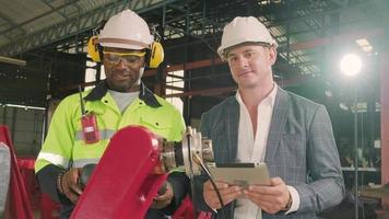 An African American engineer demonstrates smart robotic arm control to customer in mechanical manufacturing factory, intelligent automatic machines in industrial business, and futuristic technology. video