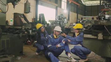 Overworked male industrial engineer worker exhausted and faints, colleague helping first aid at manufacturing factory. Safety uniforms and helmets can protect from metalwork accidents from machines. video