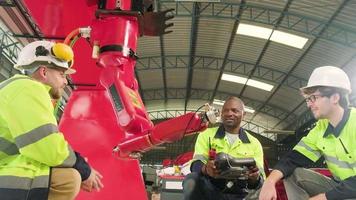 maschio produzione ingegneri squadra discutere, test, e controlli robotica braccio nel meccanico produzione fabbrica, intelligente automatico macchine nel industriale attività commerciale, e futuristico tecnologia innovazione. video