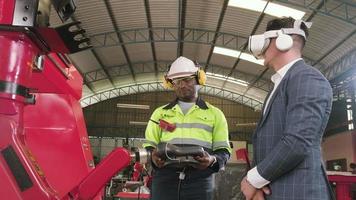 African American engineer demonstrates robotic arm control to customer with VR headsets simulator in mechanical manufacture factory, intelligent industrial machines, and futuristic technology. video