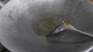 Close-up of pouring oil into a frying pan for cooking. Cook pours oil into a frying pan. Slow motion video