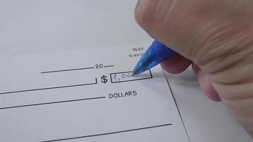 male hand writing money numbers on check on the table. video