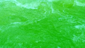 Defocus blurred transparent green colored clear calm water surface texture with splashes and bubbles. Trendy abstract nature background. Water waves in sunlight. Green water shining background. video