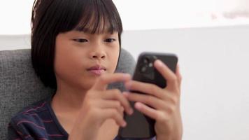 fille assise et regardant le téléphone à la maison, enfant fille video