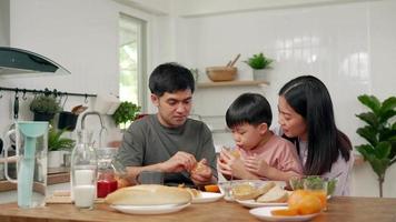konzept aktivitäten familie im urlaub. Eltern und Kinder essen in den Ferien gemeinsam. der Sohn gibt vor, seinen Vater mit Brot zu füttern. video