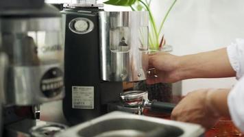 le barista prépare le café selon la recette. le propriétaire d'un petit café prépare du café avec des grains de café arabica pour servir aux clients. le barista a mis du café moulu dans la cafetière. video