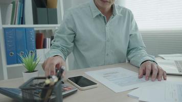 l'homme de bureau vérifie les documents et calcule la facture et numérise pour payer la facture. un homme utilise un scan de téléphone pour vérifier les détails selon les documents. concept scan qr code pour payer en ligne. video