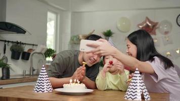 Father and mother are hosting a birthday party for their son is 5 years old. Father and mother take a picture and live video for grandmother and grandfather on social distance.