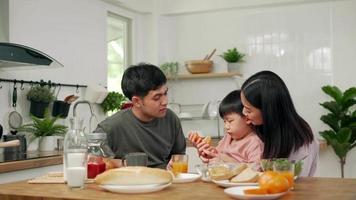 concetto attività famiglia su vacanze. genitori e bambini siamo avendo un' pasto insieme durante il vacanze. il figlio è fingendo per alimentazione il suo padre pane. video