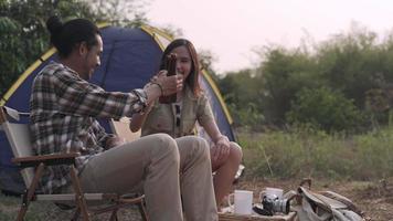 homens e namoradas estão curtindo bebida e natureza enquanto acampam. homens e mulheres acampam de férias para um feriado. conceito de recreação e camping. video