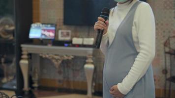A 4 month pregnant woman enjoys singing karaoke and dancing to the beat of the song. good-natured woman video
