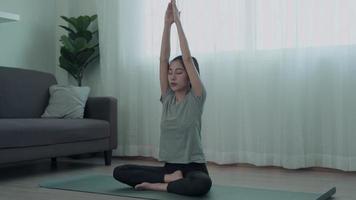 mujer delgada de asia practicando yoga en condominio. hermosa mujer haciendo ejercicios en la mañana. equilibrio, recreación, relajación, calma, buena salud, feliz, relax, estilo de vida saludable, reducir el estrés, pacífico. video