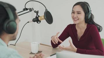 mujer y hombre hablando en una estación de radio matutina transmitiendo un programa de noticias y hombres preparando el contenido a través de computadoras. la mujer está probando el micrófono mediante una prueba de habla. programa de radio concepto. video