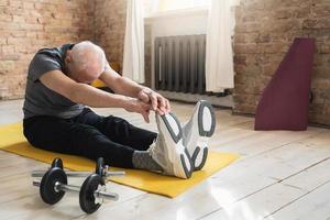 anciano activo estirándose durante su entrenamiento de fitness en casa foto