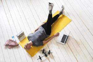 Active elderly man exercising on a yellow mat during his fitness workout photo