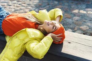 Stylish girl wearing yellow puffer and orange knitted hat photo