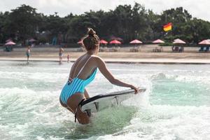 Woman surfer is going out from the ocean to the coast after her surfing workout photo