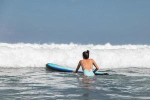 Woman surfer is trying to get into line up trough waves during her surfing workout photo