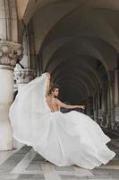 mujer joven con un hermoso vestido blanco en un arco cerca de la piazza san marco foto