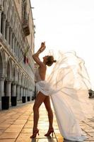 Woman wearing beautiful white dress walking on a street of the Venice city photo