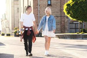 pareja adolescente con un longboard durante su cita en una ciudad foto