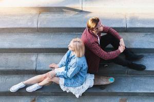 Stylish teenage couple is sitting on a concrete stairs photo