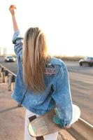 Carefree woman with a longboard on a bridge at sunset photo