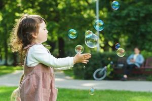 Little girl catching soap bubbles in a city park photo