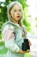 Cute little girl with a retro binoculars in a city park photo