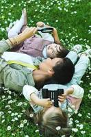 Happy family in a park. Mother and two daughter lying in chamomile field. photo