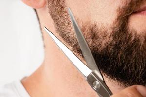 Man trimming his beard with a scissors photo