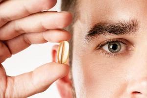 Man holding capsule with a fish or krill oil source of fatty acids such as DHA and EPA photo