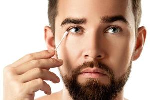 Man cleaning his eye with a cotton swab photo