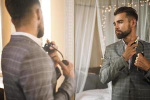 Handsome bearded man is using atomizer nozzle with perfume photo