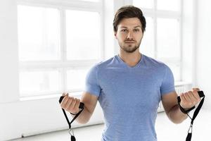 Young handsome man during workout with a resistance rubber bands in the gym. photo