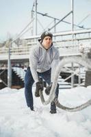 Young athlete working out with a battle ropes during snowy winter day. photo