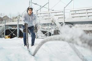 Young athlete working out with a battle ropes during snowy winter day. photo