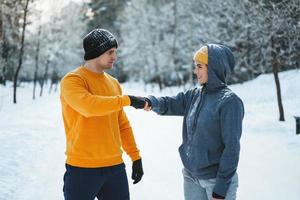 Two joggers greeting each other with a fist bump gesture during winter workout photo