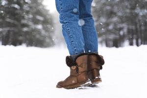 Woman wearing sheepskin boots walking by snowy road photo